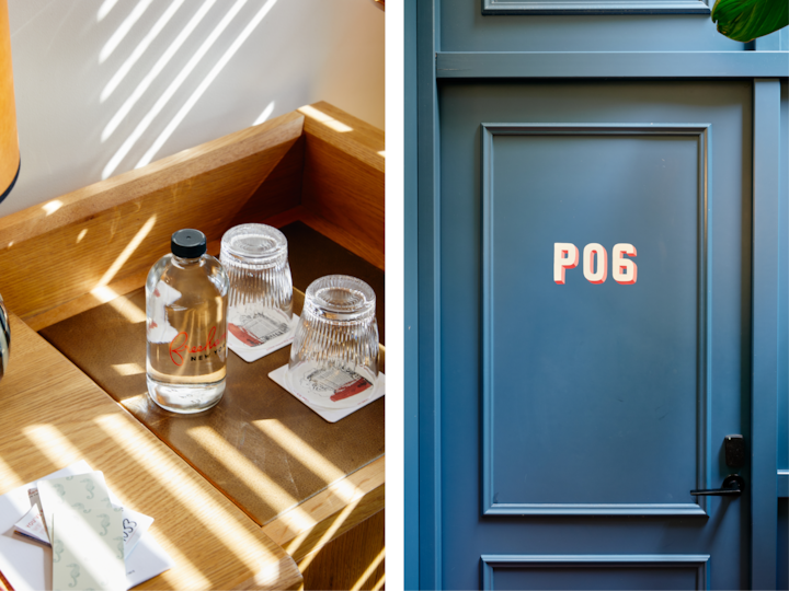 Un plateau en bois sur lequel se trouvent une bouteille d'eau de marque et deux verres posés sur des dessous de verre, éclairé par une douce lumière du soleil, à côté d'une porte bleue élégante portant l'inscription « P06 » en lettres rouges et blanches.