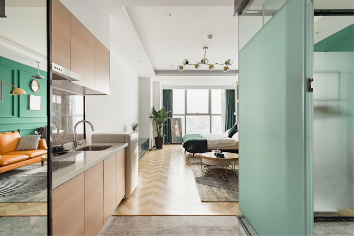 Aménagement d'un appartement contemporain comprenant une cuisine élégante, un salon dynamique avec des touches de vert et d'orange, et une chambre paisible avec de grandes fenêtres et une vue sur la ville.