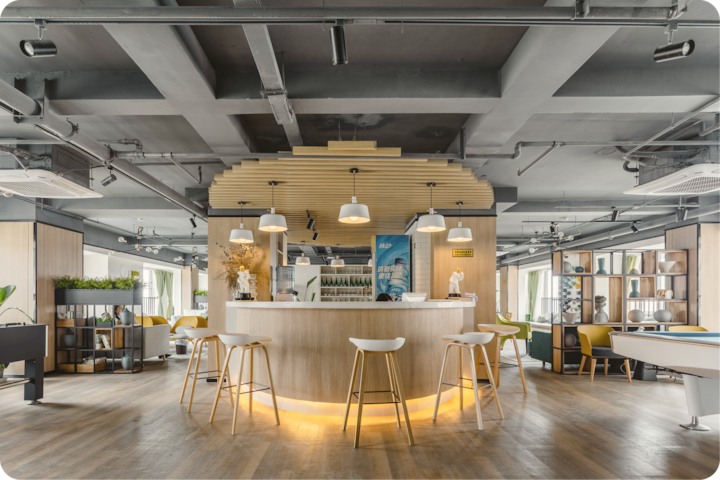 Un espace élégant dans un hôtel, avec un bar central à l'éclairage doux, des éléments en bois et des meubles contemporains dans un cadre lumineux et ouvert.