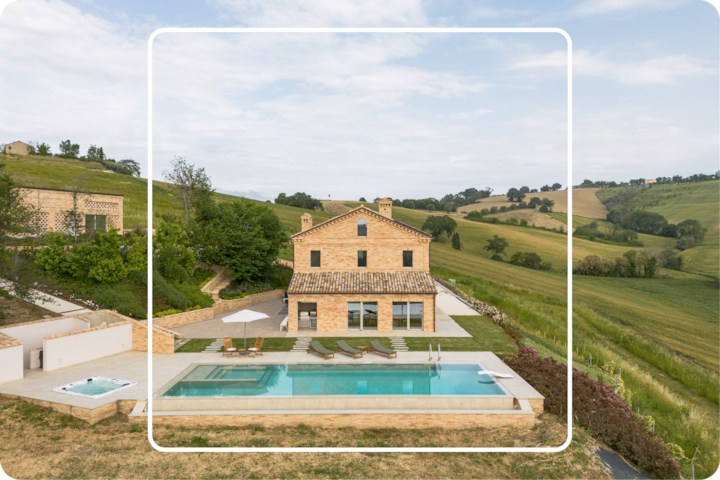 Vue aérienne d'une villa paisible avec piscine et jacuzzi, située dans un paysage pittoresque et luxuriant de champs et de collines.