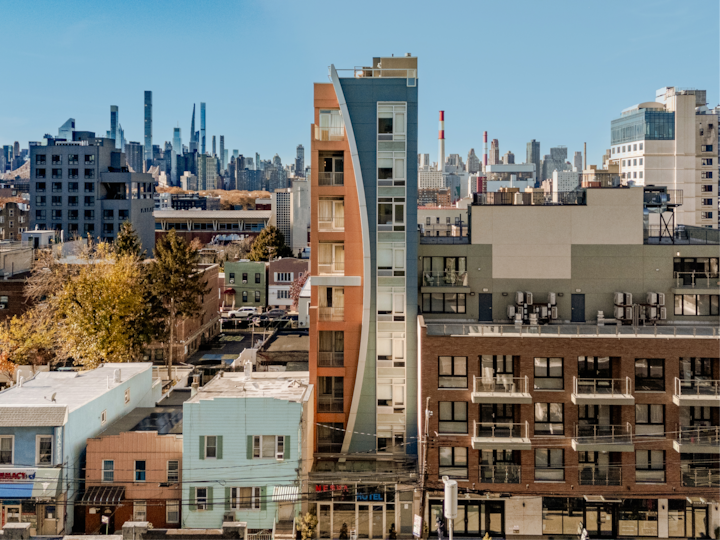 Un hôtel moderne à l'architecture incurvée, situé au cœur d'un quartier urbain dynamique, avec des gratte-ciel de la ville visibles en arrière-plan.