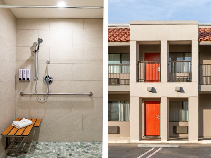 Une douche accessible dotée d'équipements de sécurité, notamment des barres d'appui et un banc, à côté de l'extérieur d'un motel aux portes rouge vif et au toit de style terre cuite.