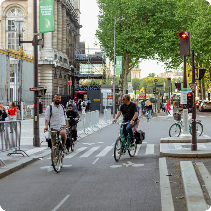 Une rue parisienne animée avec une piste cyclable  où circulent plusieurs cyclistes.