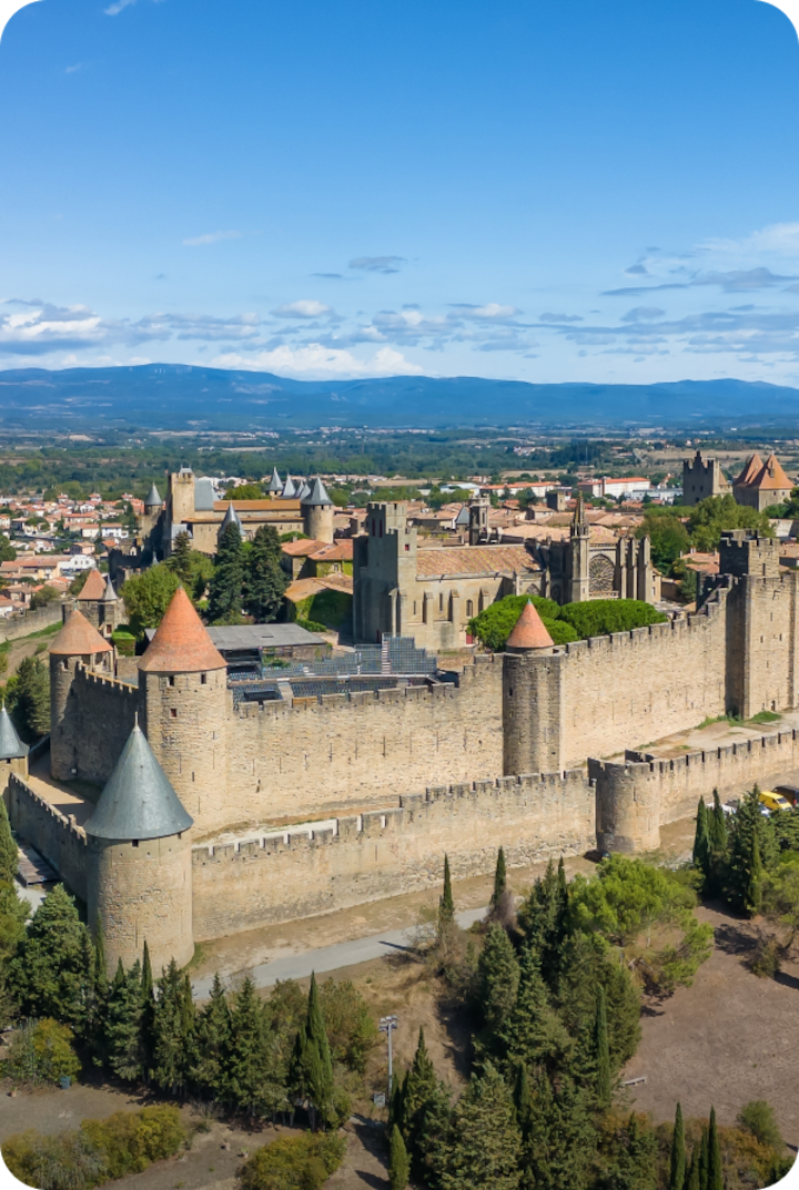 Vue panoramique de Lannemezan avec des montagnes à l'horizon et quelques nuages blancs. Texte superposé : « Étape 5 – Lannemezan », avec une flèche vers la droite.