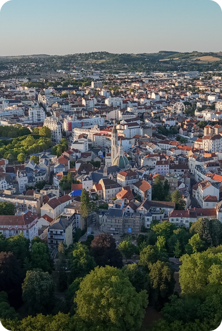 Vue aérienne de Vichy, mêlant toits rouges et bâtiments clairs, entourés de parcs et d'arbres. Texte superposé : « Étape 11 – Vichy », avec une flèche vers la droite.