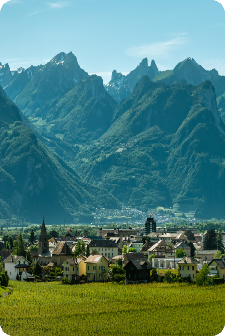 Vue panoramique de la ville d'Aigle entourée de vignobles et de champs. Texte superposé : « Étape 2 – Aigle », avec une flèche vers la droite.