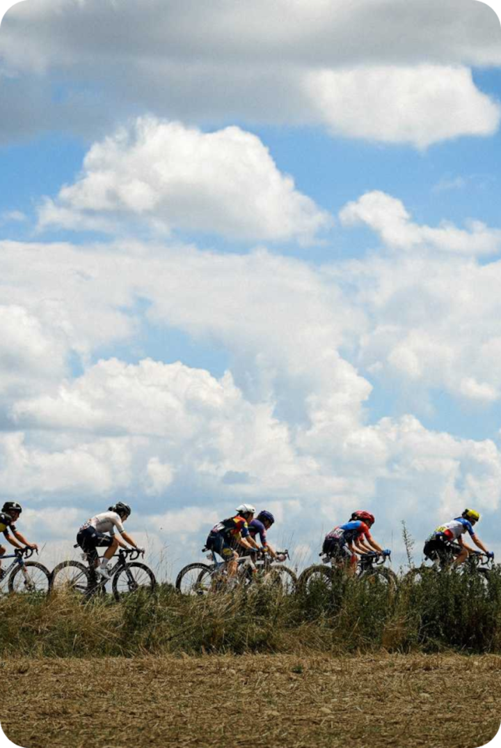 Des cyclistes professionnels roulent en peloton sur une route de campagne sous un ciel bleu. Texte superposé : « Étape 6 – Montbrison », avec une flèche vers la droite.
