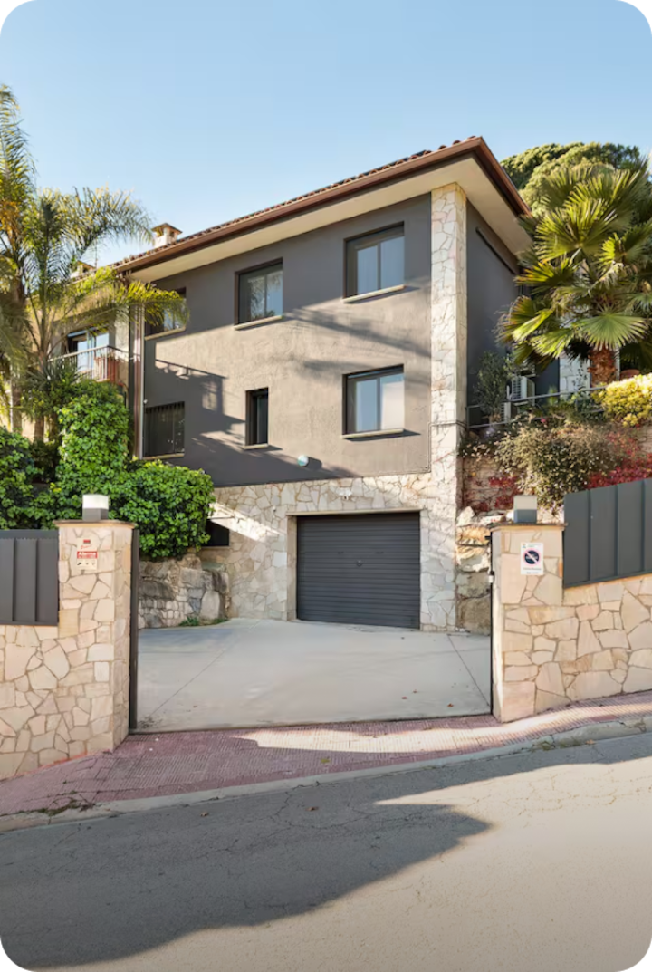 Une maison moderne à deux étages avec façade en pierre et porte de garage grise. Texte superposé : « Étape 3 – Granollers », avec une flèche vers la droite.