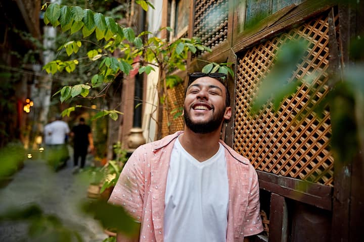Young man laughing in street with eyes closed