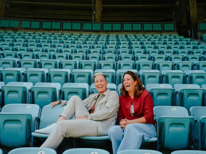 Two people relax in empty stadium seats, suggesting a quiet moment beyond the football match.