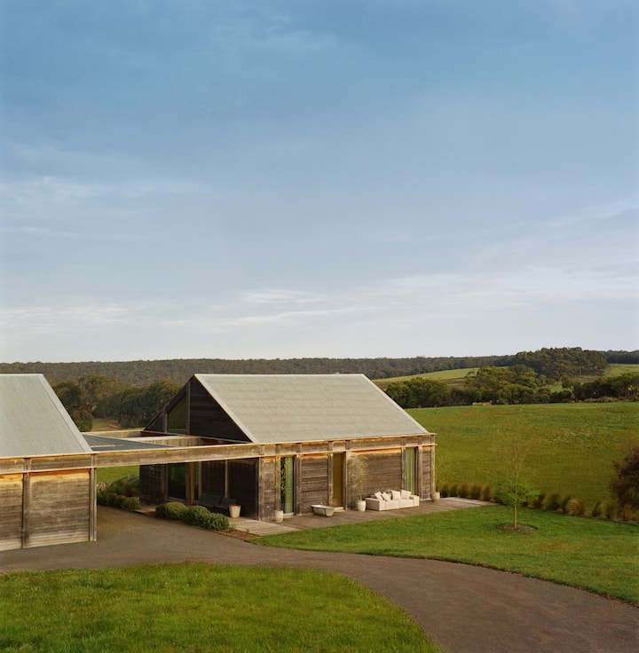 Anúncio de uma acomodação moderna em estilo celeiro no meio do campo, sugerindo que você receba seus primeiros hóspedes no Airbnb em um refúgio tranquilo.