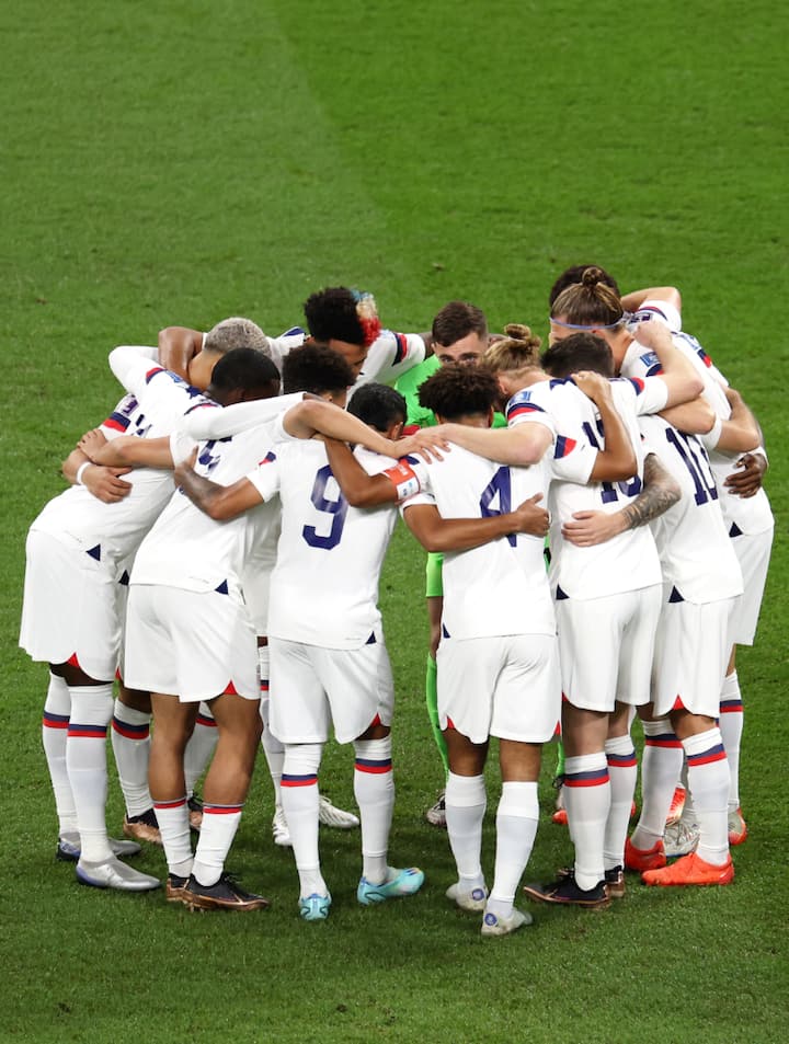Un equipo de fútbol con uniforme blanco se reúne en el campo antes de un partido de la Copa Mundial de la FIFA