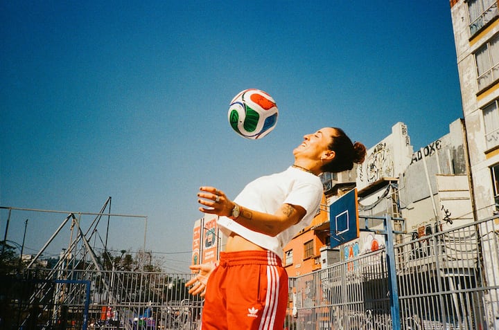 Person in a city courtyard bouncing a FIFA soccer ball off their head in Mexico City.
