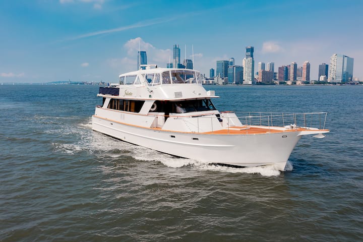Un yacht de luxe navigue dans le port de New York avec la silhouette de Manhattan à l'arrière-plan