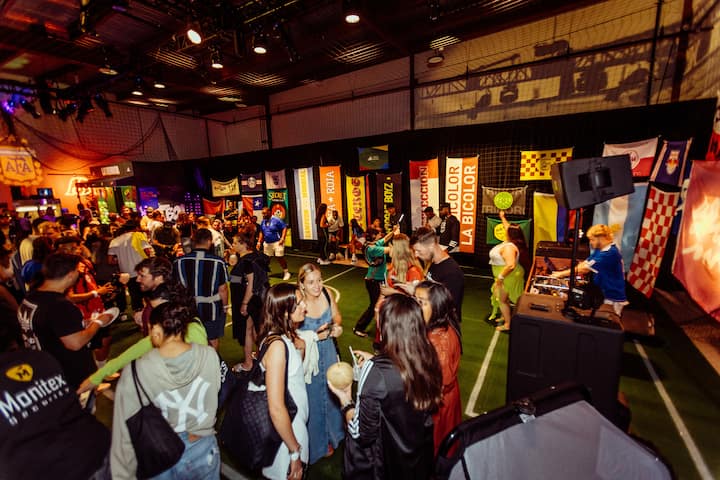 Une foule participe à une expérience pour les fans de la FIFA en intérieur à New York, avec des banderoles de football suspendues aux murs.