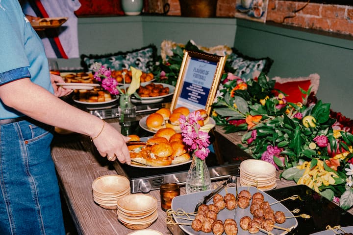 Assortiment coloré de plats de fête et de fleurs lors d'une expérience FIFA à New York, dans lequel une personne est en train de se servir