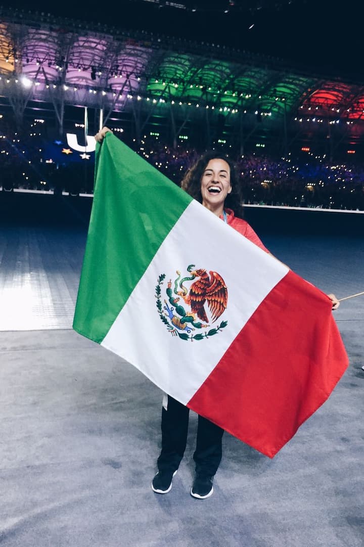 Person celebrates at a packed FIFA stadium in CDMX, proudly waving a Mexican flag