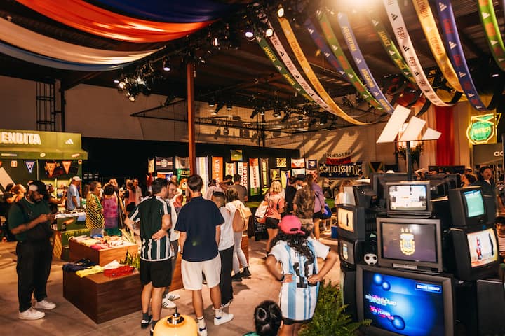 Expérience pour les fans de la FIFA à New York, dans un cadre intérieur avec stands d'articles de football, banderoles suspendues et écrans de télévision.
