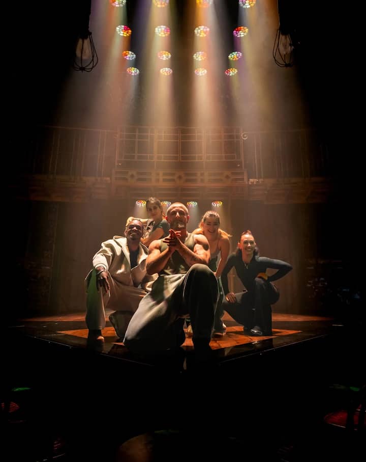 Cast and guests posing and clapping on stage after a performance