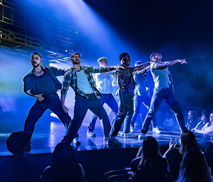 Cast and guests posing and clapping on stage after a performance