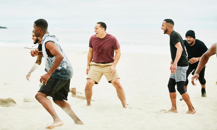 Amigos jugando un juego de playa dinámico en la arena, cerca de la orilla del mar.