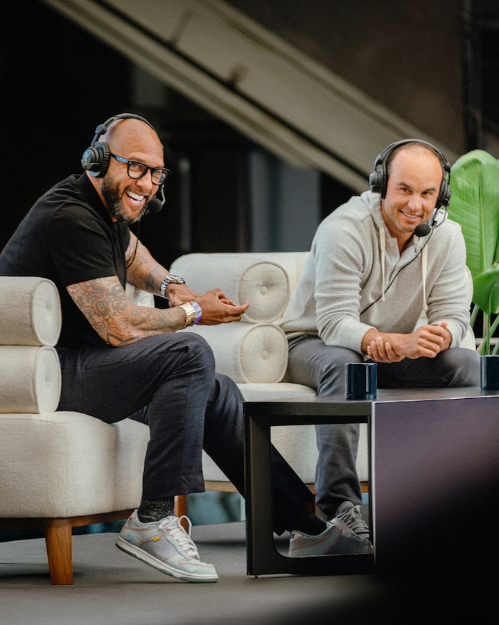 Landon Donovan et Tim Howard sont assis sur des chaises confortables, des casques d'écoute sur les oreilles, prêts pour la diffusion.