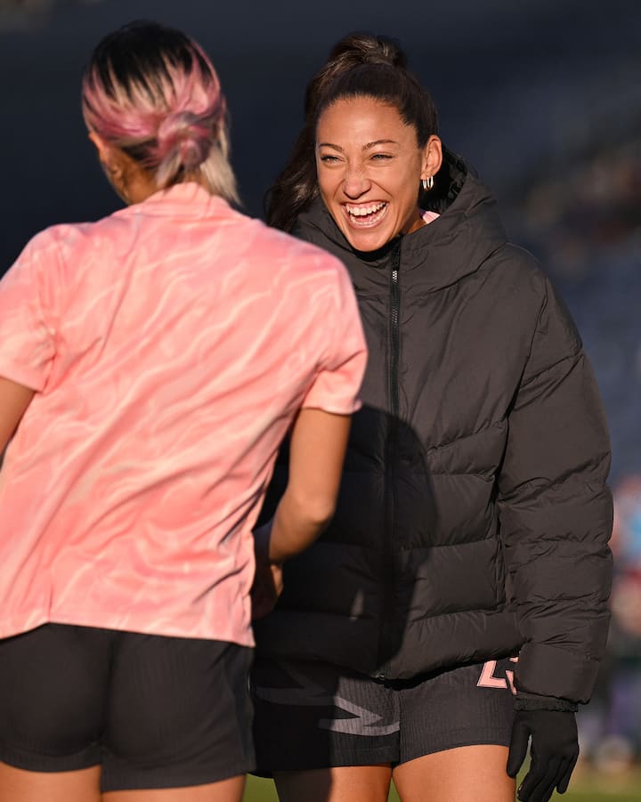 Christen Press sourit en saluant une autre joueuse de soccer.
