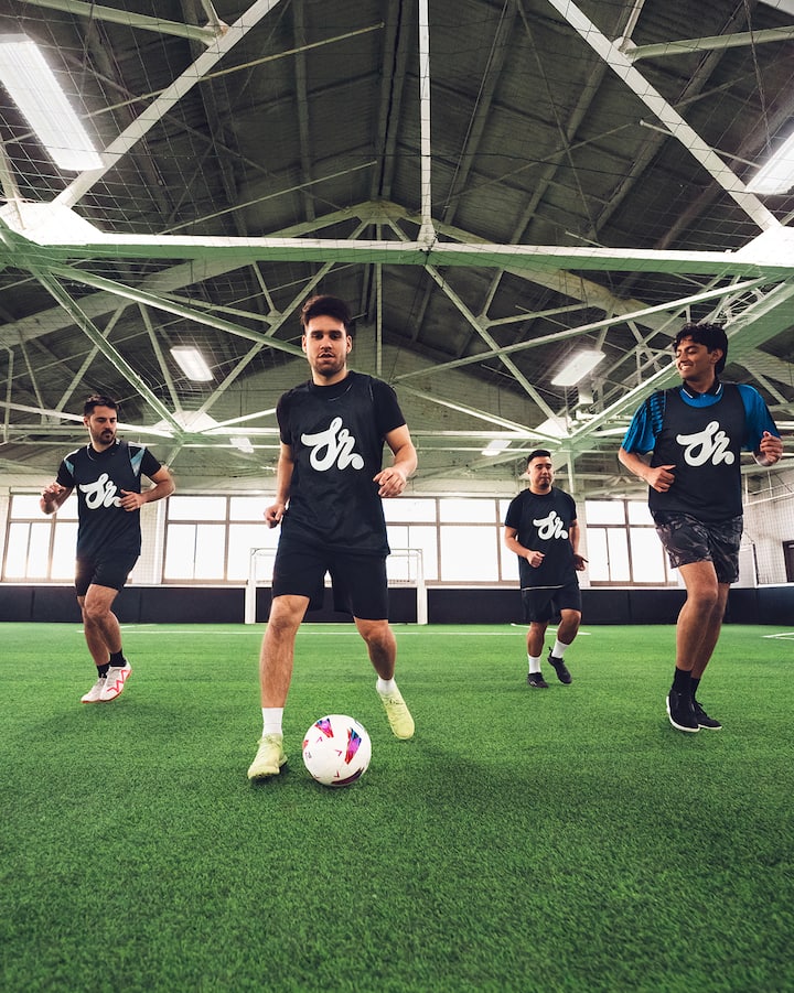Des joueurs de soccer dribblent sur un terrain intérieur.