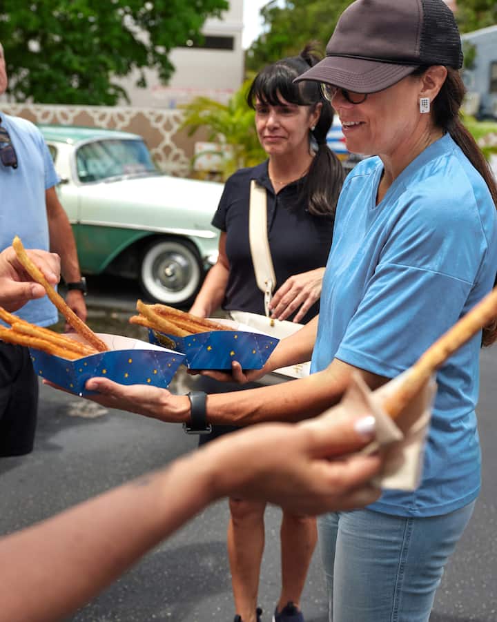 Une femme portant un maillot de soccer distribue des churros à un petit groupe.