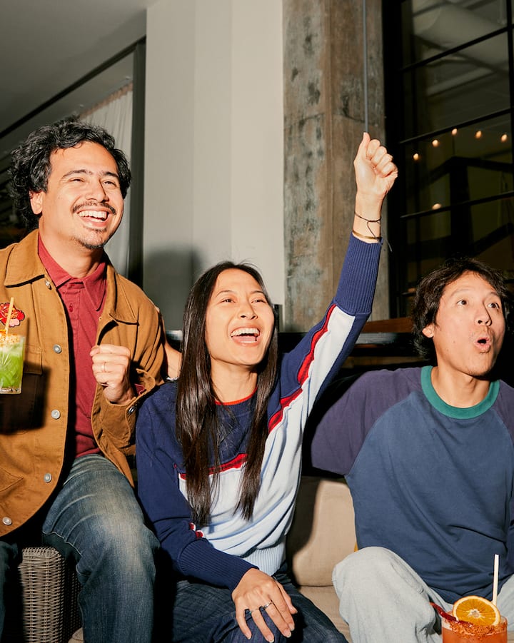 Des amis assis sur un sofa encouragent leur équipe en regardant le match.
