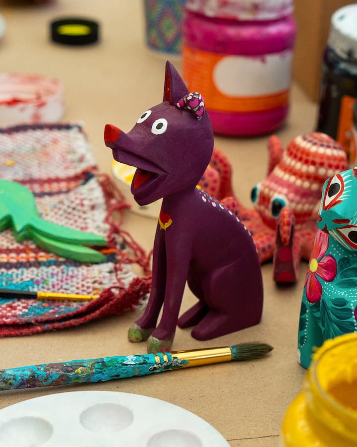 Un gros plan sur une sculpture de chat violet posée sur un bureau entouré de matériel pour artistes.