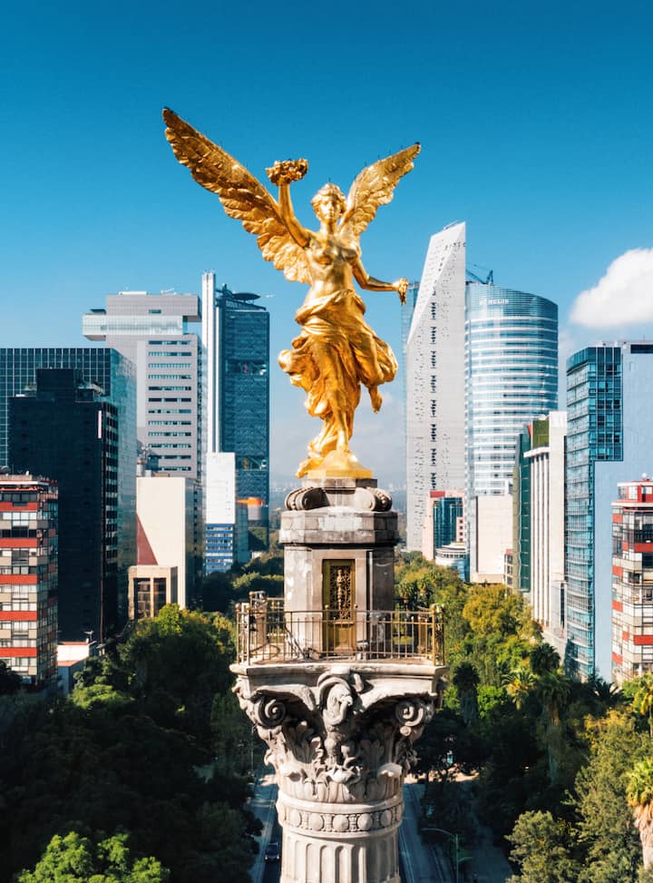 Golden Angel of Independence statue towering over Mexico City’s modern skyline, concept art for an Airbnb FIFA city page. View more listings in CDMX.