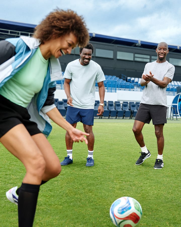 Trois joueurs de soccer se passent un ballon sur un terrain extérieur.