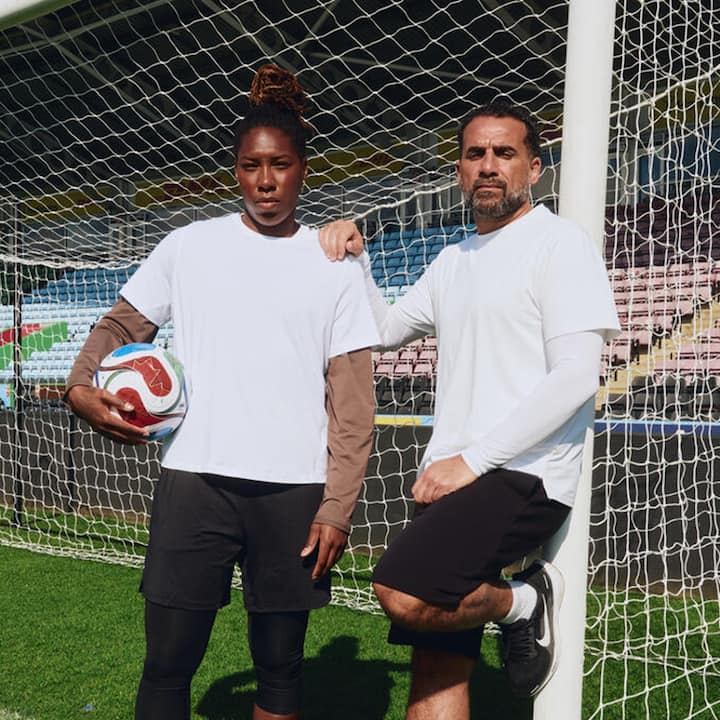 Two soccer players in white jerseys pose by the goalpost at Toronto Stadium with a ball, ready for a match.