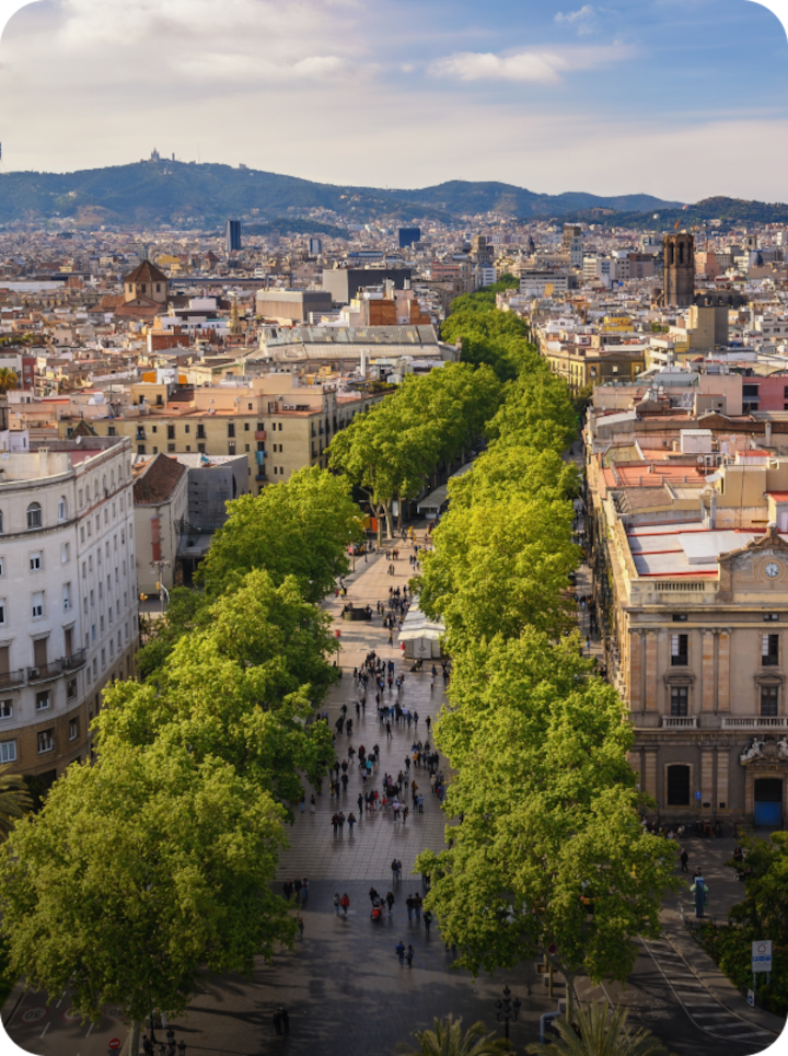 Une grande avenue piétonne bordée d'arbres à Barcelone. Texte superposé : « Étape 1 Barcelone », avec une flèche vers la droite.