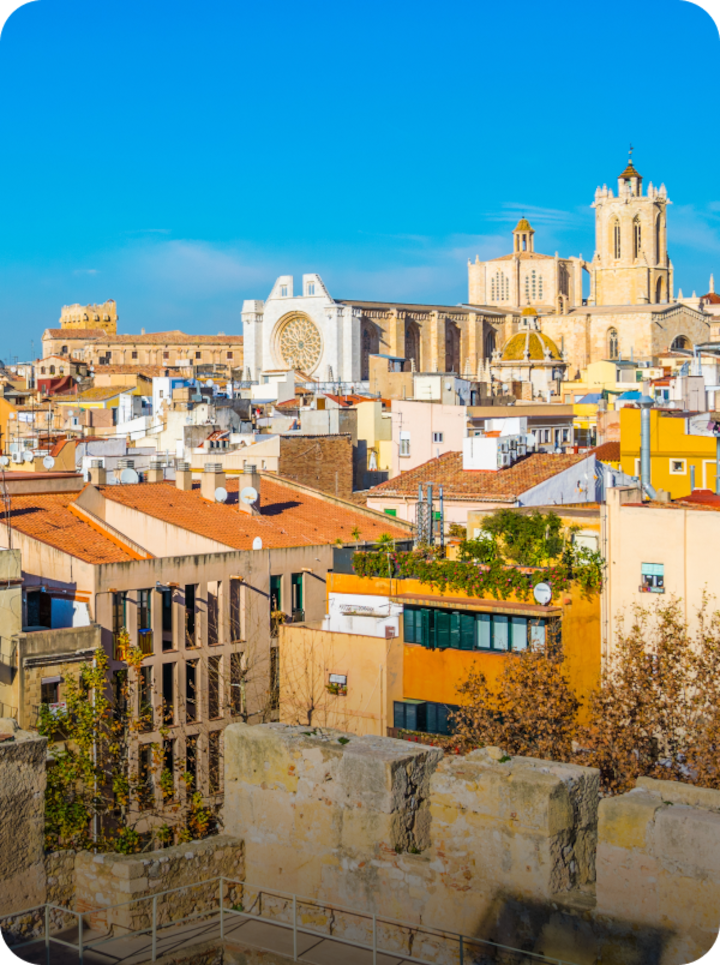 Vue de la ville de Tarragone sous un ciel bleu éclatant. Texte superposé : « Étape 2 Tarragone », avec une flèche vers la droite.