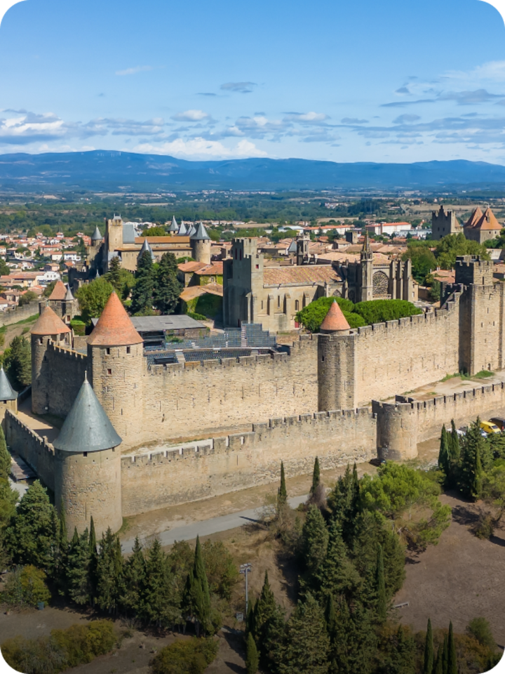 Un rempart de la cité de Carcassonne. Texte superposé : « Étape 4 Carcassonne », avec une flèche vers la droite.