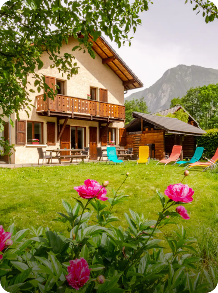Une maison rustique au Bourg-d'Oisans donnant sur un jardin verdoyant et ensoleillé, avec la mention « Étape 20 Le Bourg-d'Oisans » en bas à gauche et une flèche vers la droite.