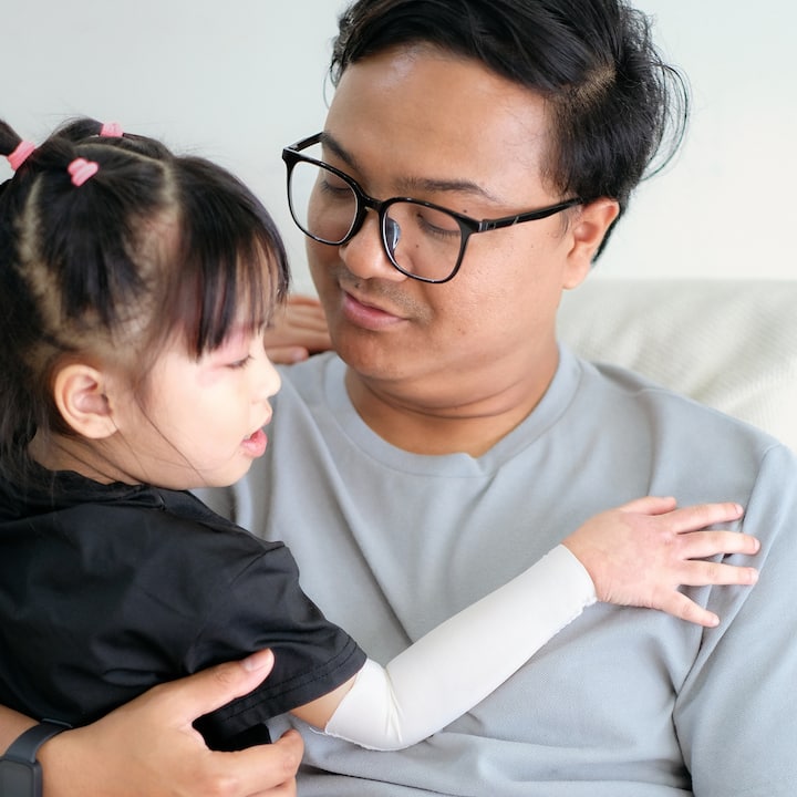 Adult and young child embracing on a couch, highlighting family safety and care in Southeast Asia