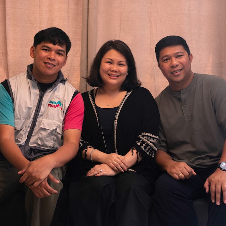 Three people seated closely together indoors, suggesting community support for Airbnb.org in Southeast Asia.