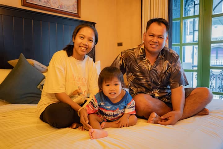 Family with a young child sitting together on a bed in a cozy Bangkok Airbnb.org stay