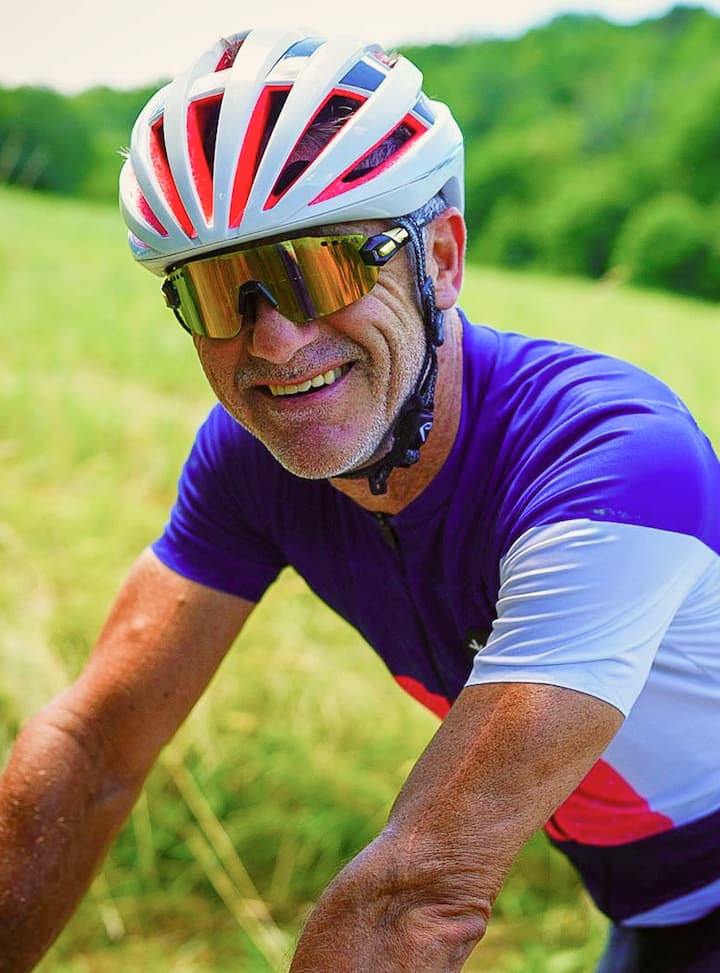 Un cycliste en maillot bleu parcourt une campagne verdoyante par une journée ensoleillée