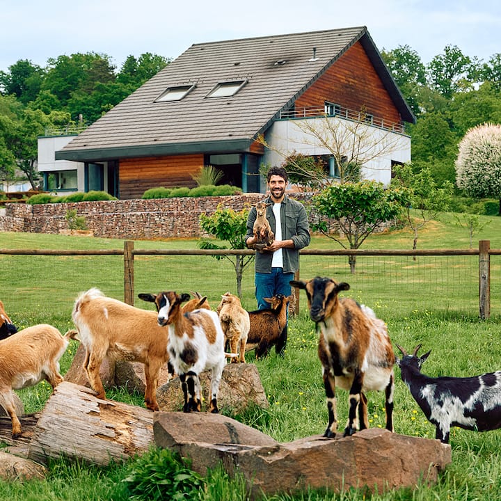 Thibaut Pinot tient un chevreau dans ses bras dans une petite ferme caprine.