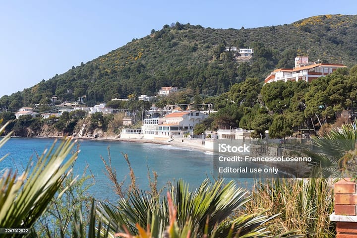Costal village in rural Italy with pastel houses on a hillside above a quiet blue bay