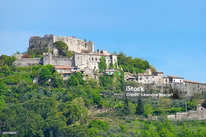 Borgo collinare italiano con castello e case in pietra immersi nel verde dell’Italia rurale.