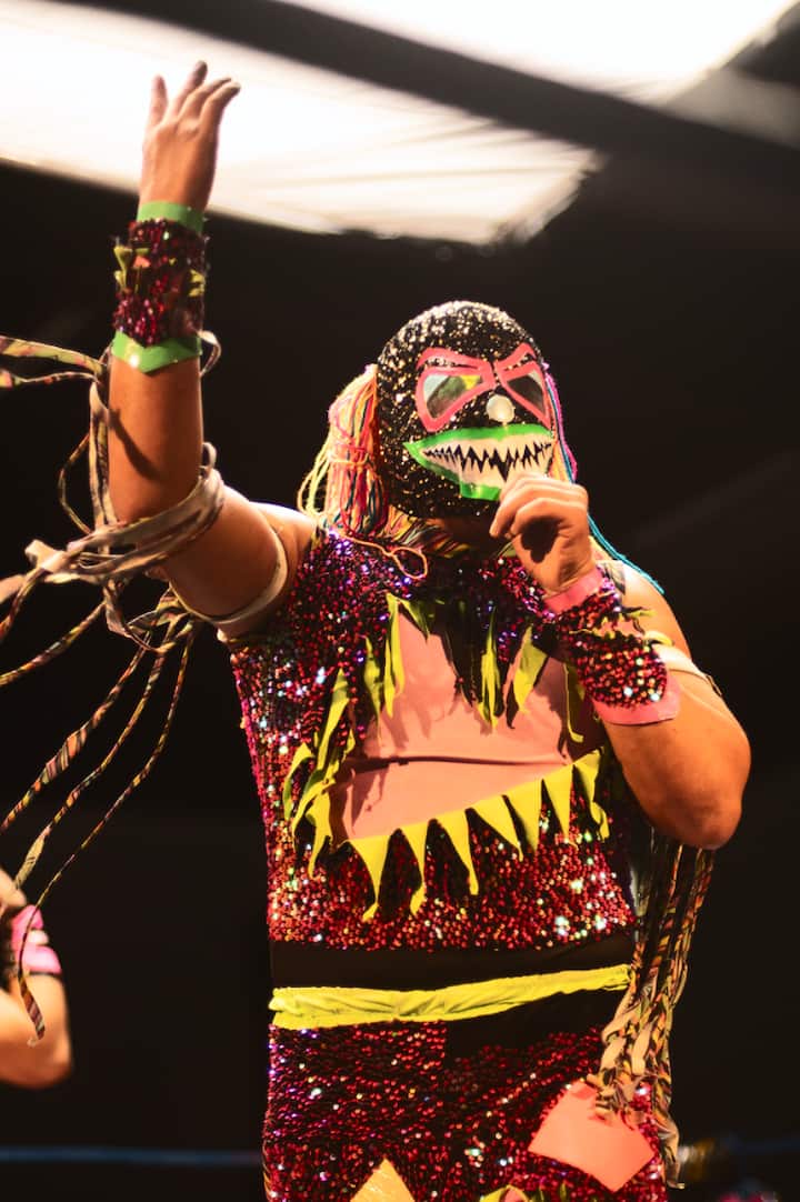 Colorful luchador performing in a sparkling mask and costume at a wrestling ring