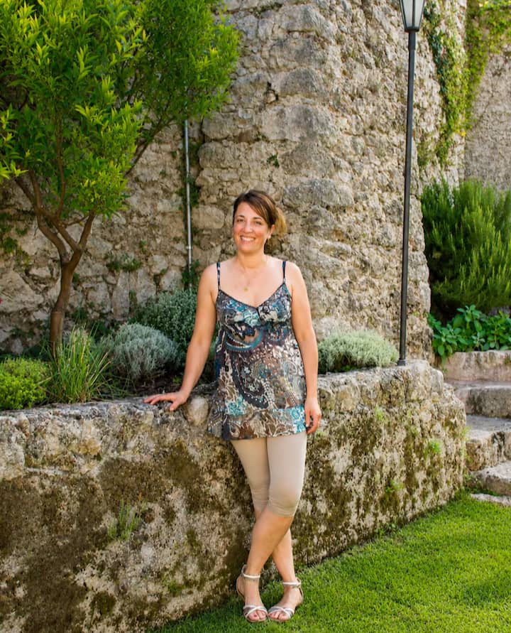 Monica appoggiata al muretto del suo borgo medievale a Vicalvi, nel giardino curato della casa di famiglia.