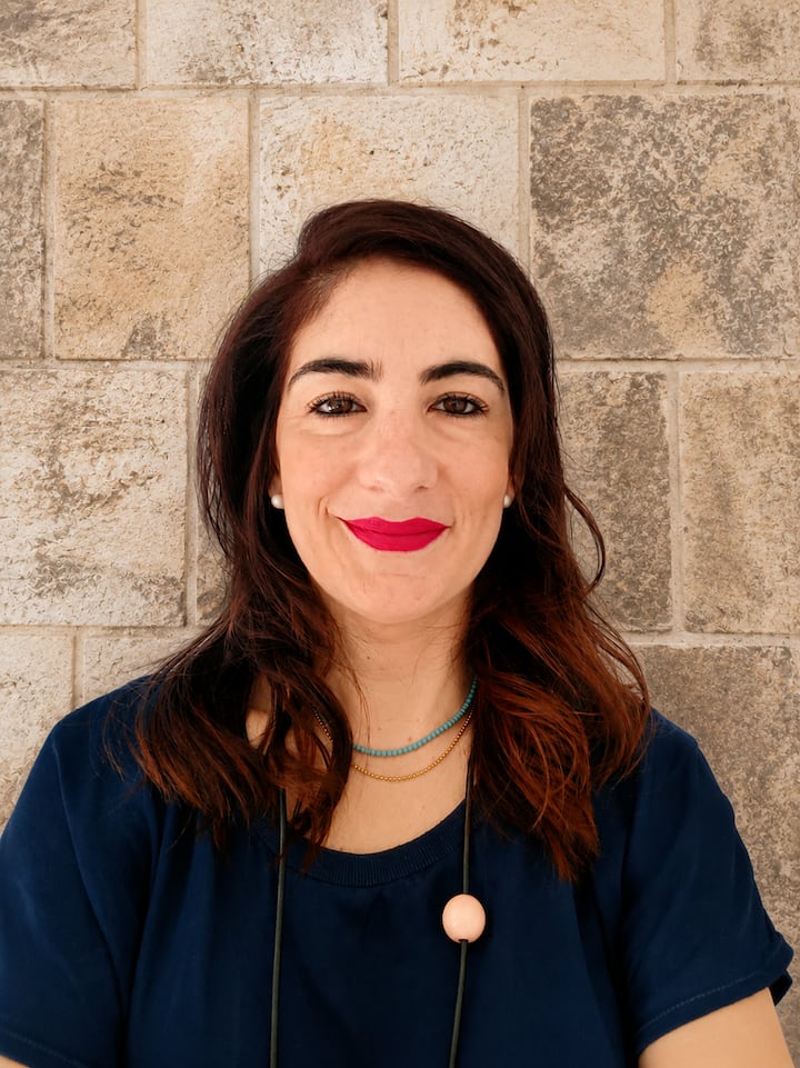 Maria Assunta standing against a leccese stone wall, symbol of Salento’s heritage and her restored family corte.