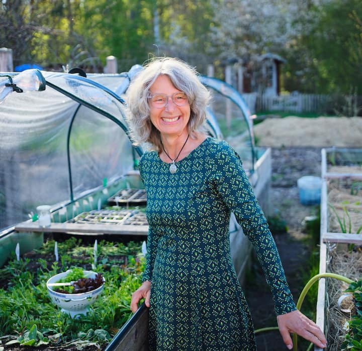 Host tending vegetable beds in a small greenhouse garden, illustrating support for Germany’s Nature Fund.