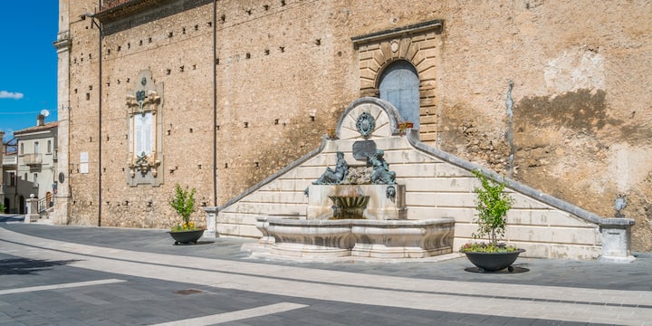 Storica fontana in pietra in una piazza silenziosa di un piccolo borgo italiano accessibile solo tramite Airbnb.